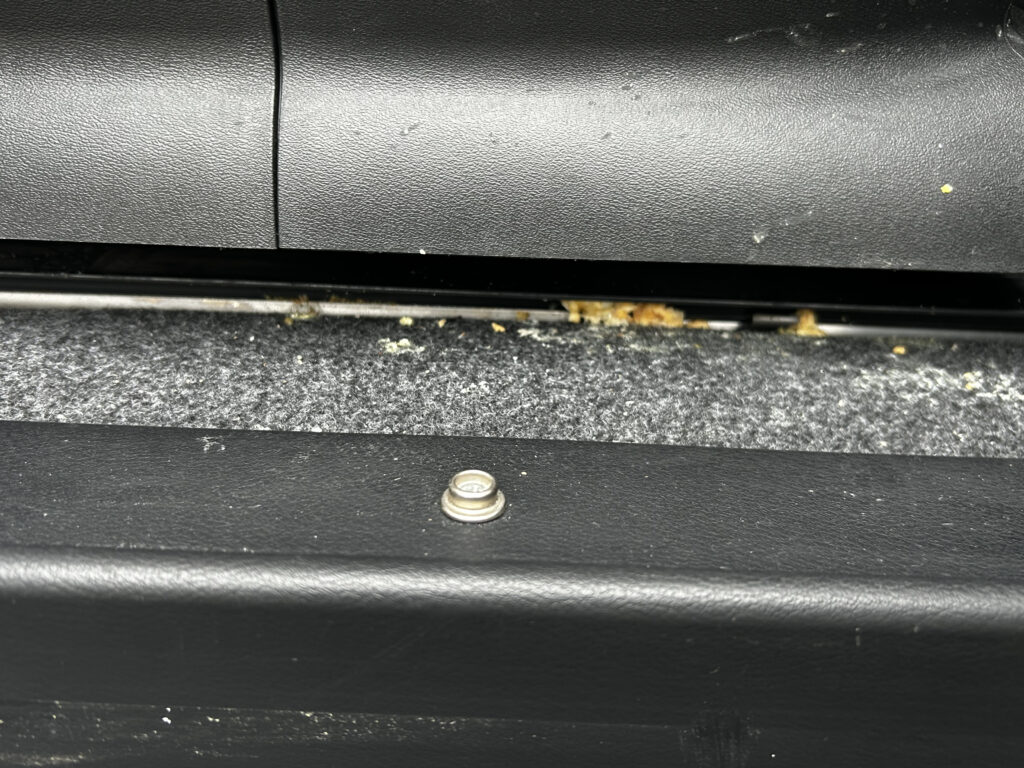 車のシートレールの隙間に入り込む吐瀉物イメージ写真