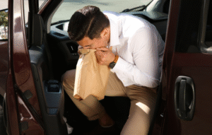 飲み会帰りの車内で嘔吐する友人男性のイメージ写真