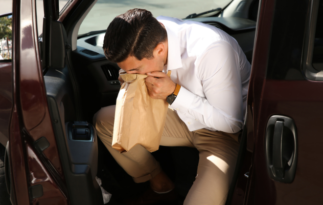 飲み会帰りの車内で嘔吐する友人男性のイメージ写真