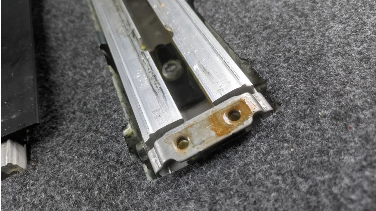 シートレール周辺の汚れを確認する車内清掃作業