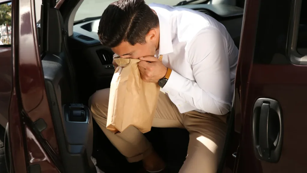 車内で気分が悪くなり袋を口元に当てている人のイメージ
