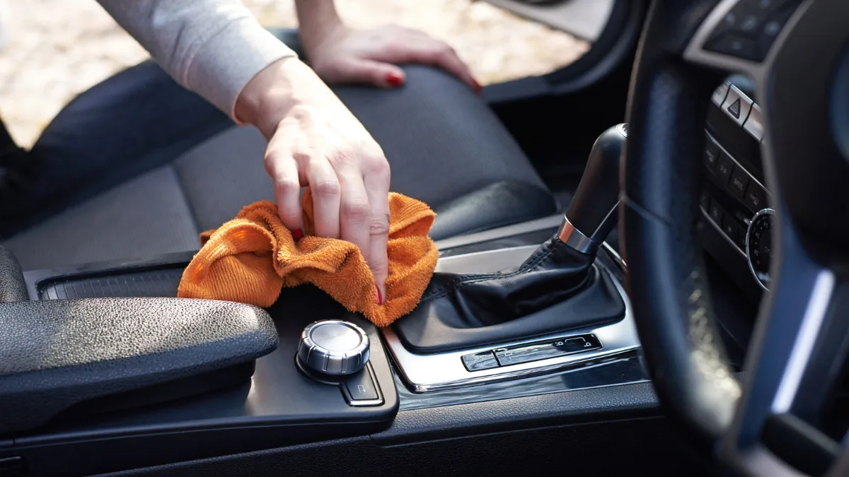 車内のセンターコンソール周辺を布で拭き取るイメージ
