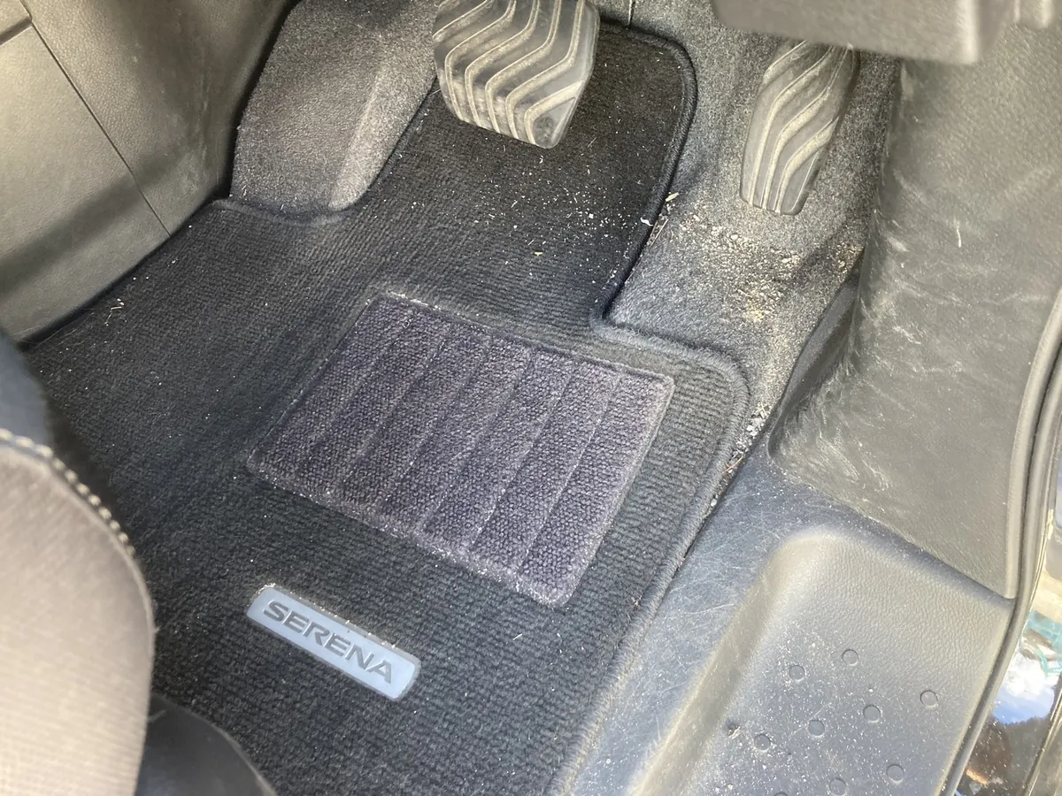 施工前の運転席足元。マットの脇、ドア開口部の縁に土砂のような粒が溜まっている状態(島根県出雲市・日産セレナ)