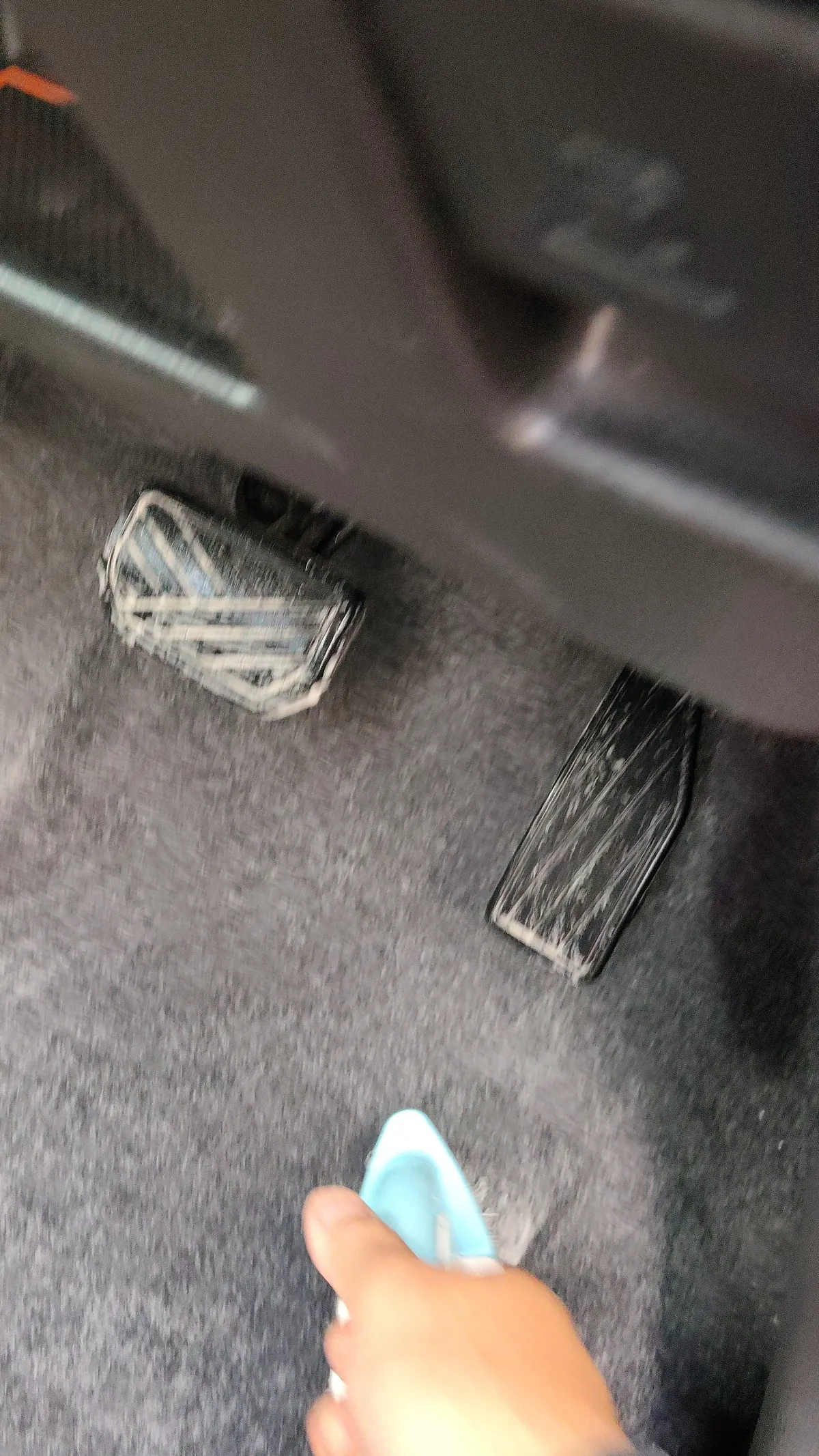 運転席の足元のカーペットをブラシでこすっているところ