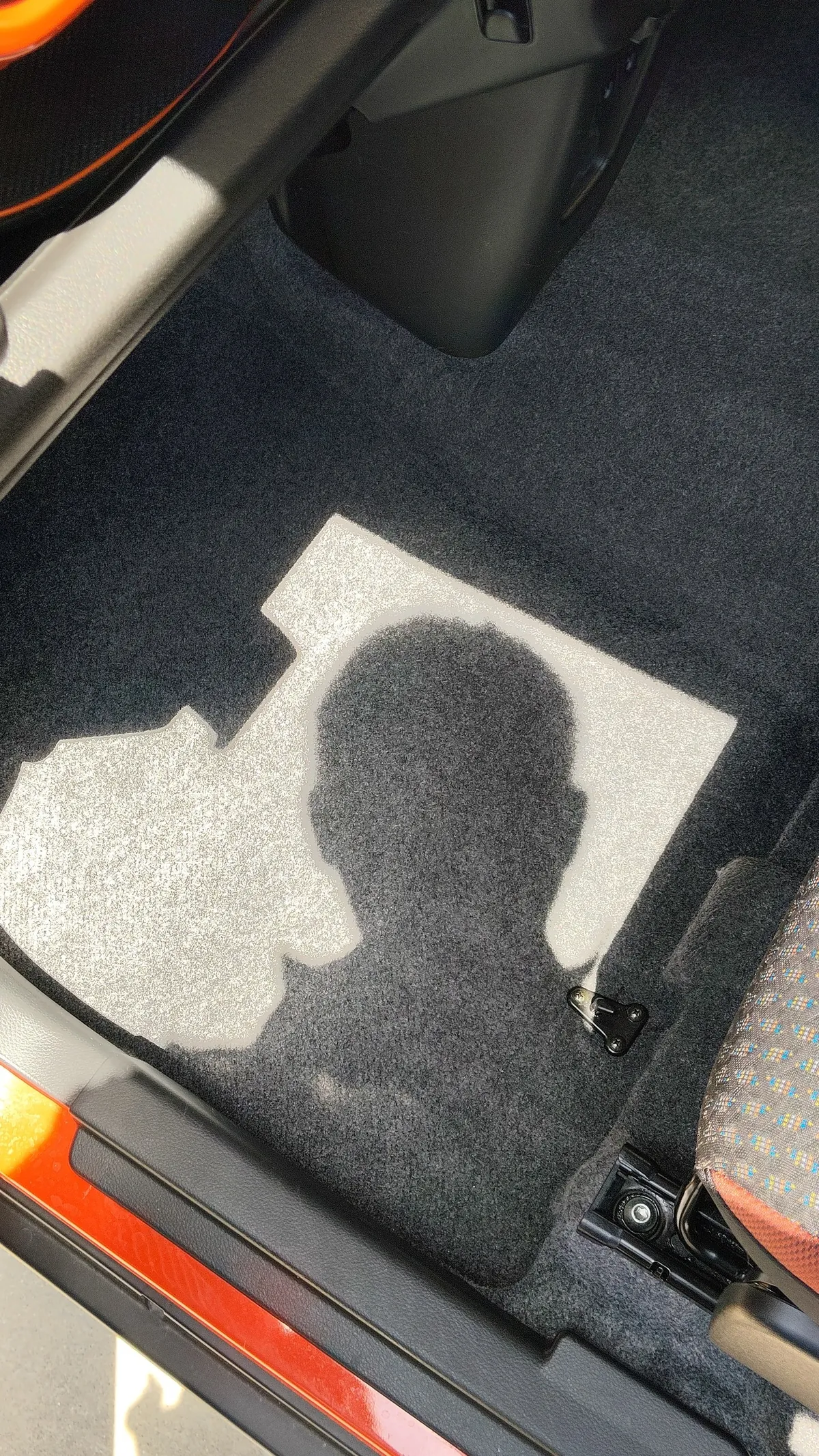 開けたドアから日が差し込んでいる助手席の足元のカーペット