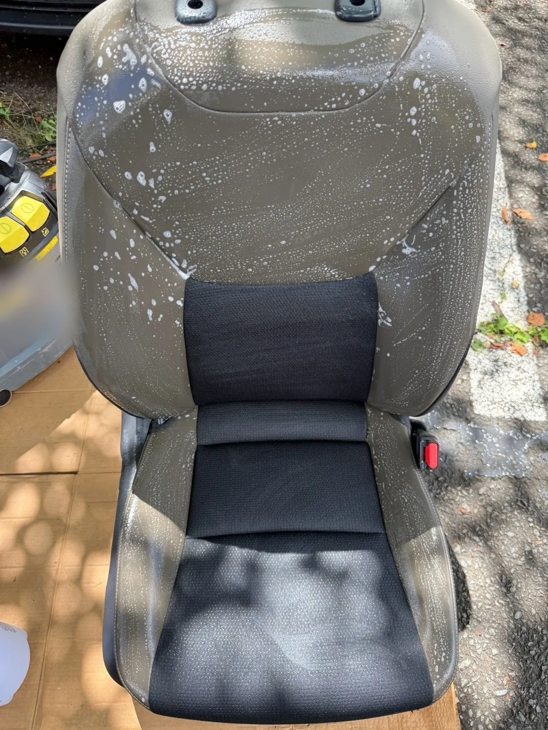 車外に取り出した運転席のシート。段ボールの上に置かれ、合皮部分が泡で覆われている