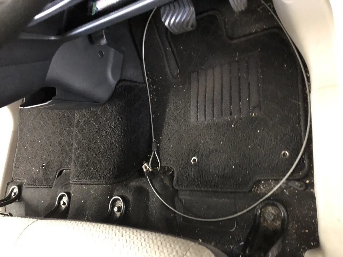 作業前の運転席足元。フロアマットの上に白っぽい粒状のものが広い範囲に散っている