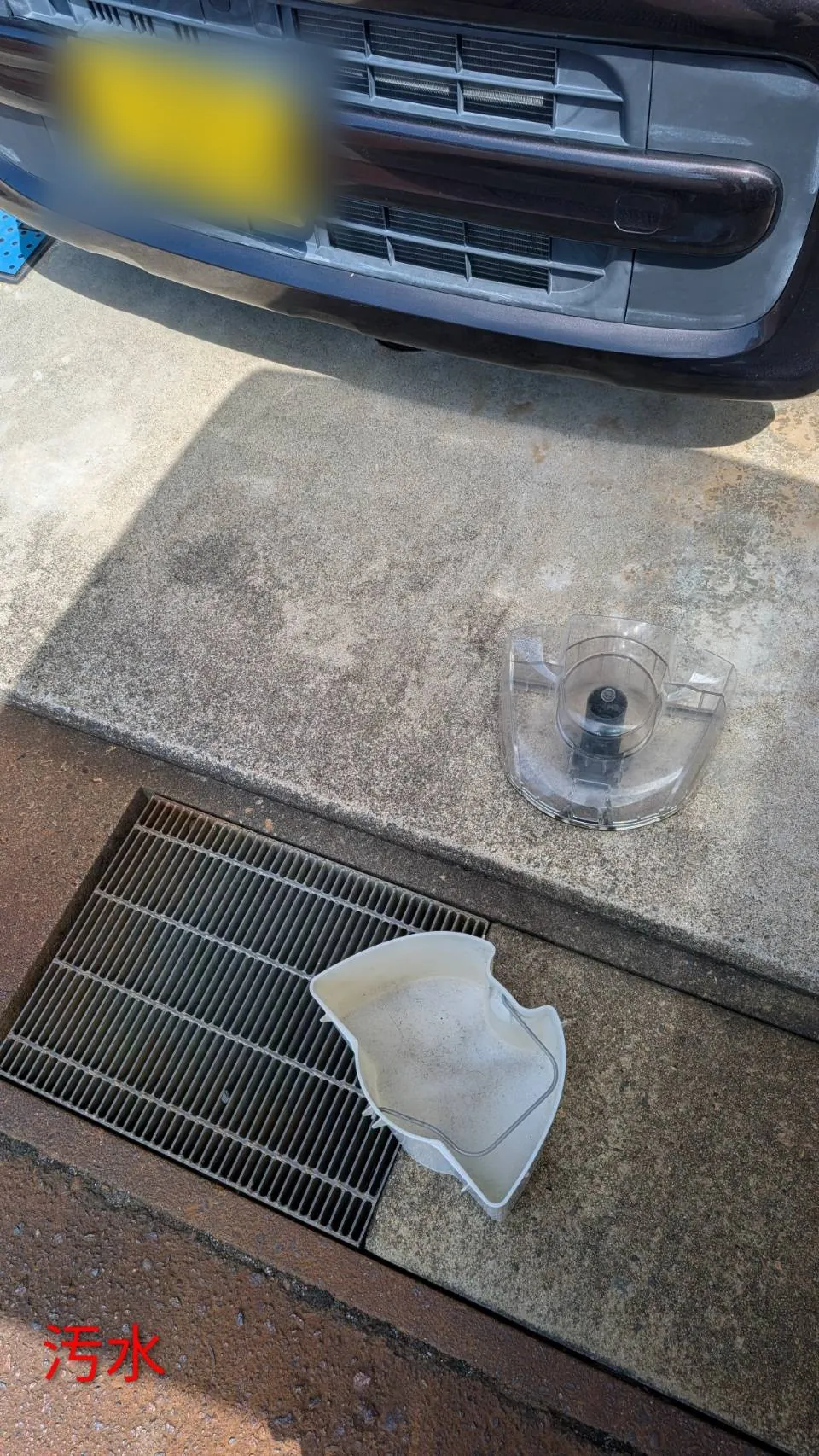 洗浄で回収した水。白い受け皿に濁った水が残っており、奥に透明のタンクの部品が置かれている