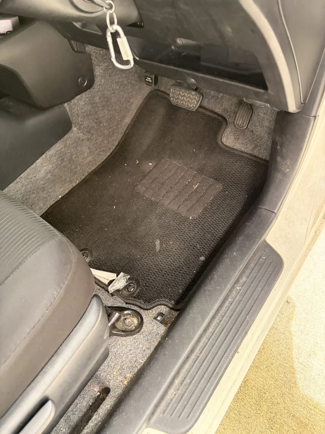 施工前のトヨタ プロボックス運転席足元。マットに粒状のゴミや紙片が散在している