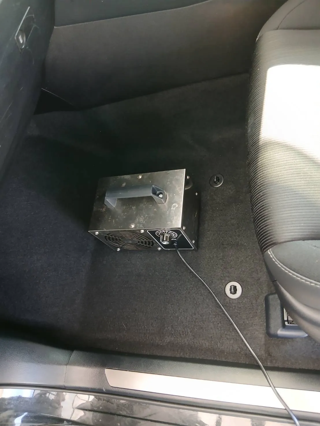 助手席の足元に置かれた黒い箱型のオゾン発生器。カーペットは元に戻っている