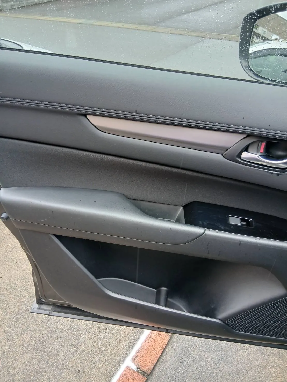 ドアを開けた状態のCX-5の内張りを外側から写したところ。地面のレンガが見える