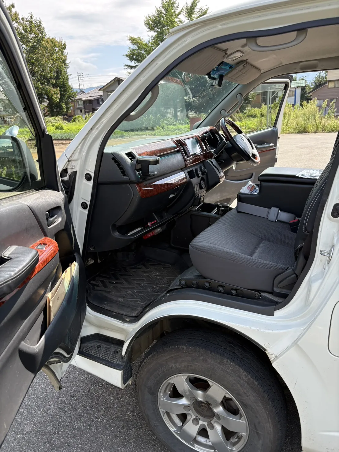 トヨタ ハイエースの運転席まわりを助手席側から見たところ。木目調のダッシュボードとハンドル（作業の前）