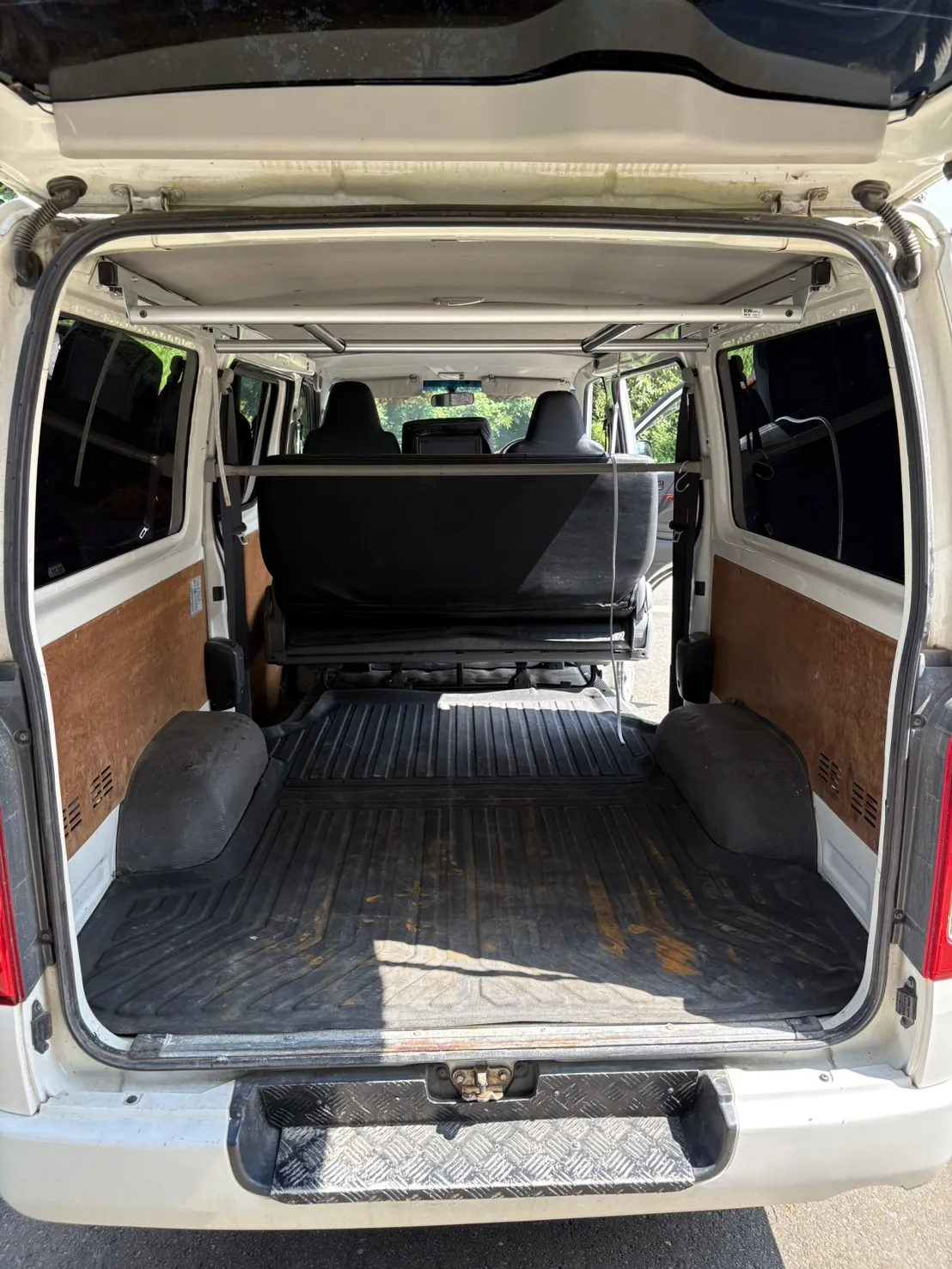 ハイエースの荷室を後ろのドアから見たところ。床一面に黒いラバーマットが敷かれている（作業の前）