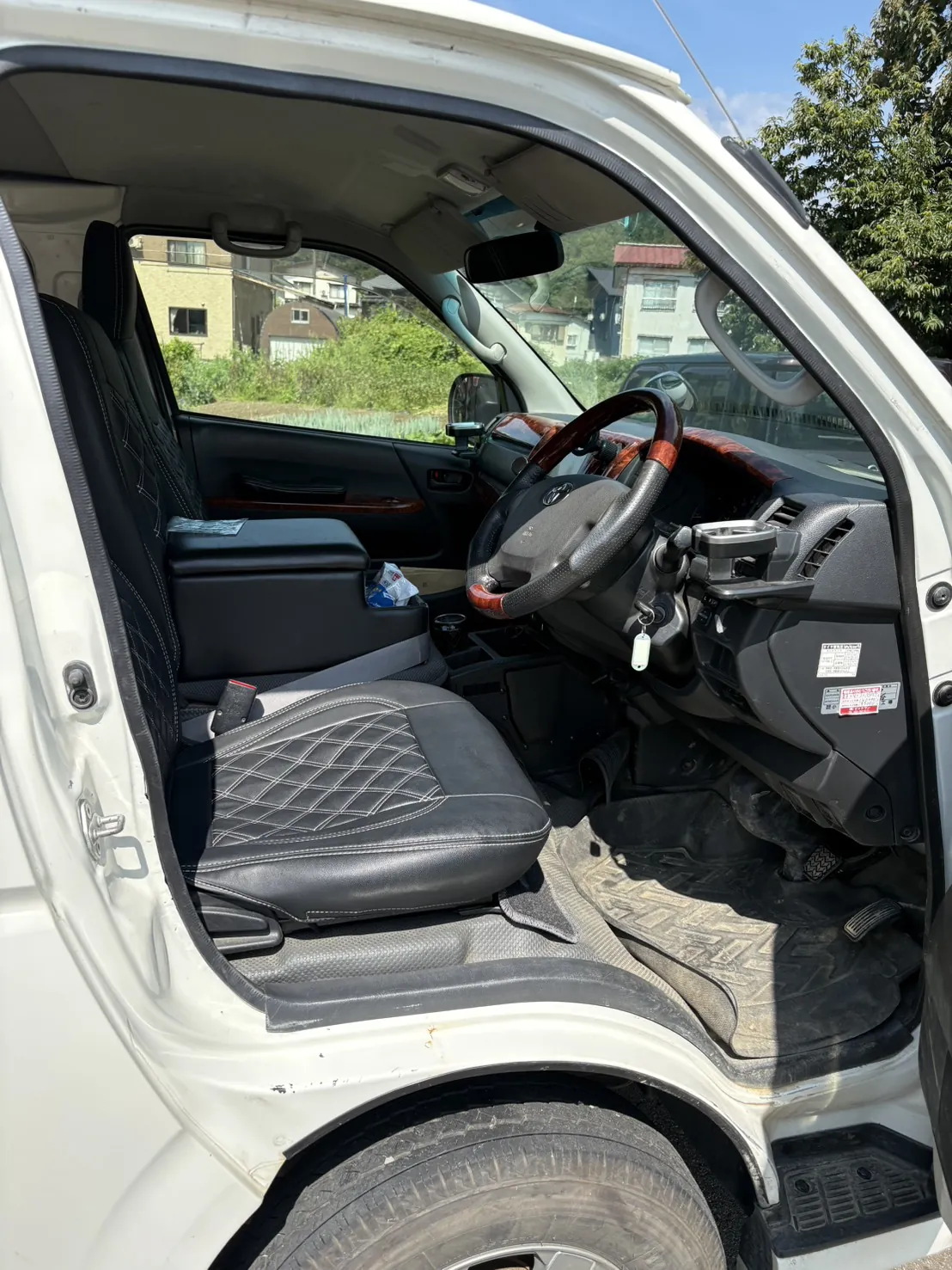 ハイエースの運転席を運転席側のドアから見たところ。キルト柄のシートカバーが付いている（作業の前）