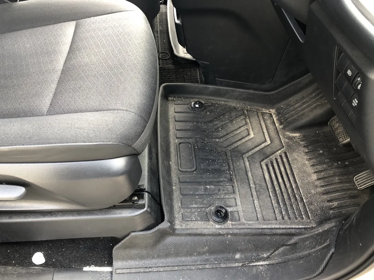 作業前の運転席の足元。黒いラバー製のフロアマットに白い細かい粒が散っている