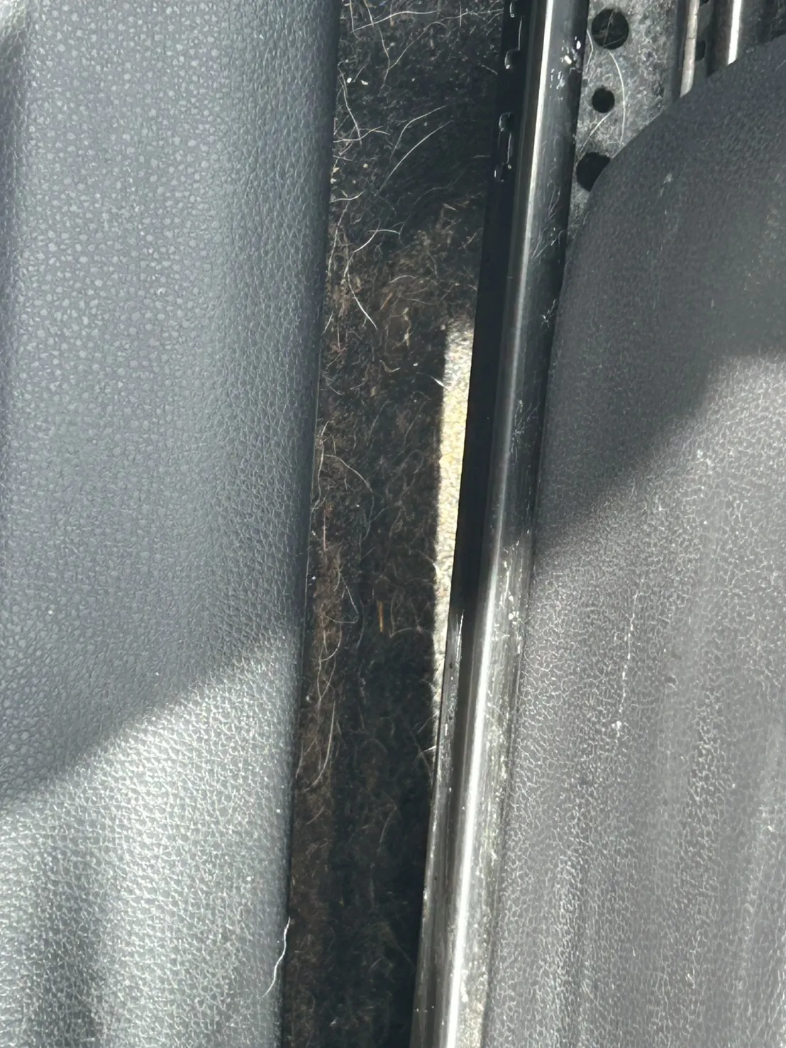 黒い樹脂の面に挟まれた細い溝。奥に細かい繊維とほこりがびっしり入り込んでいる