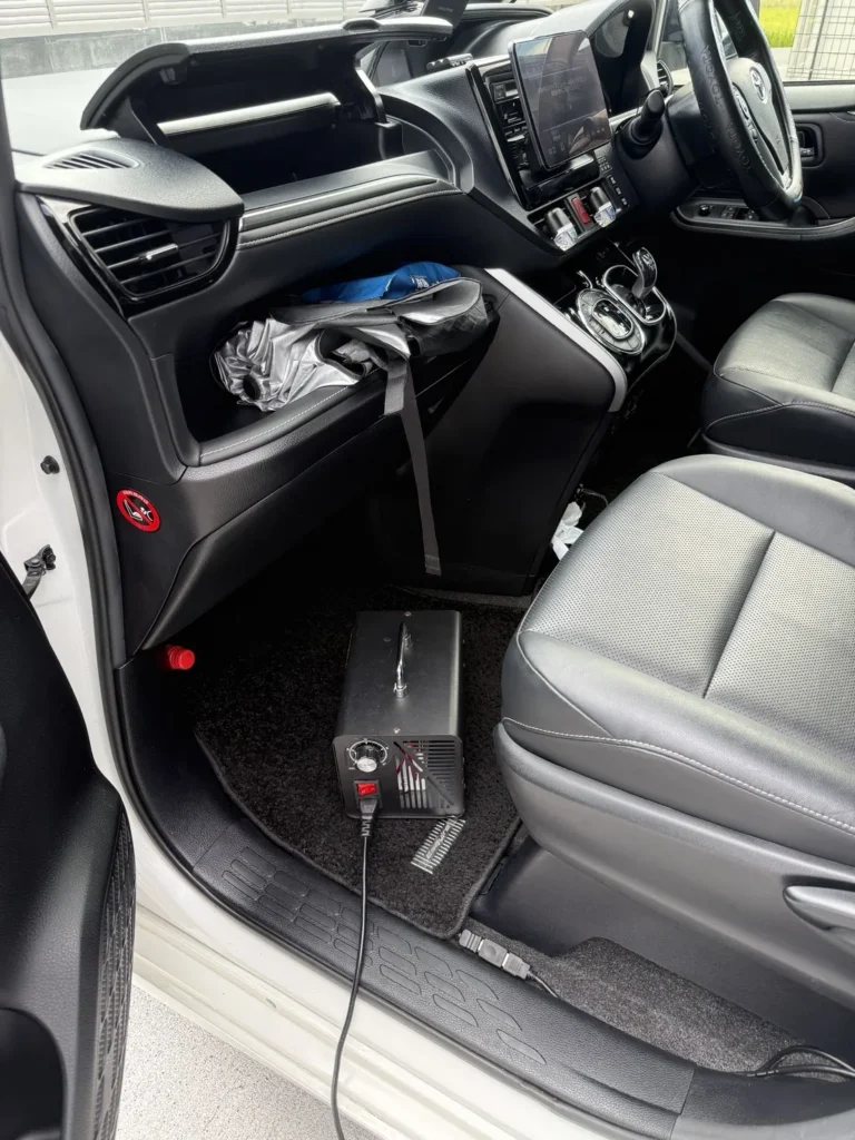 助手席の足元に置かれたオゾン発生器と、車外へ伸びる電源コード