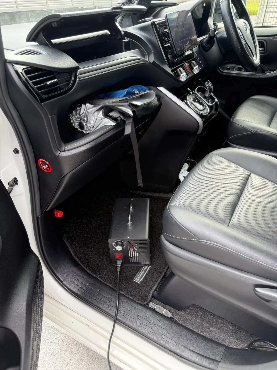 助手席の足元に置かれたオゾン発生器と、車外へ伸びる電源コード