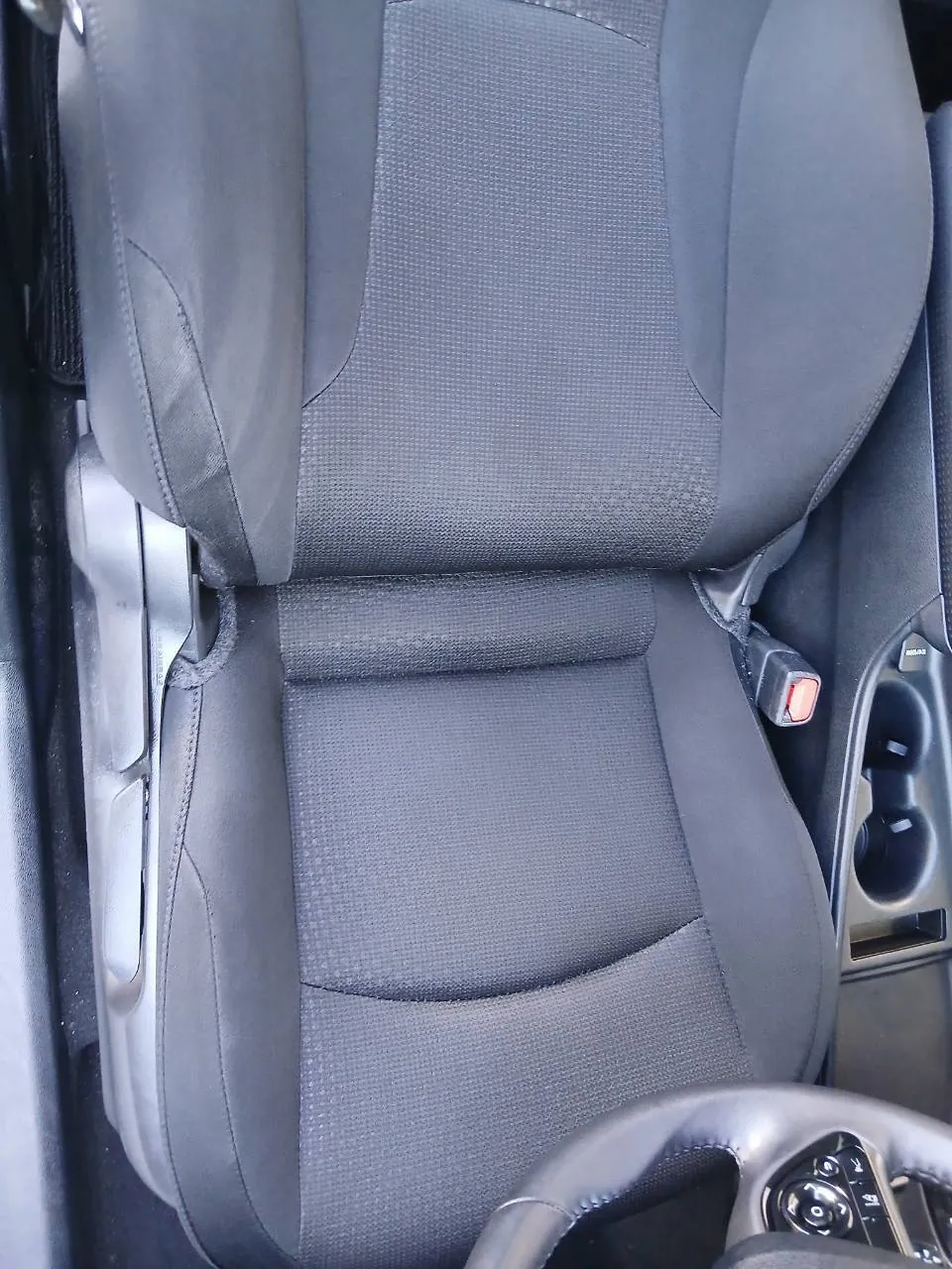 作業後の運転席の座面と背もたれ。右にシートベルトのバックルとカップホルダーが写っている