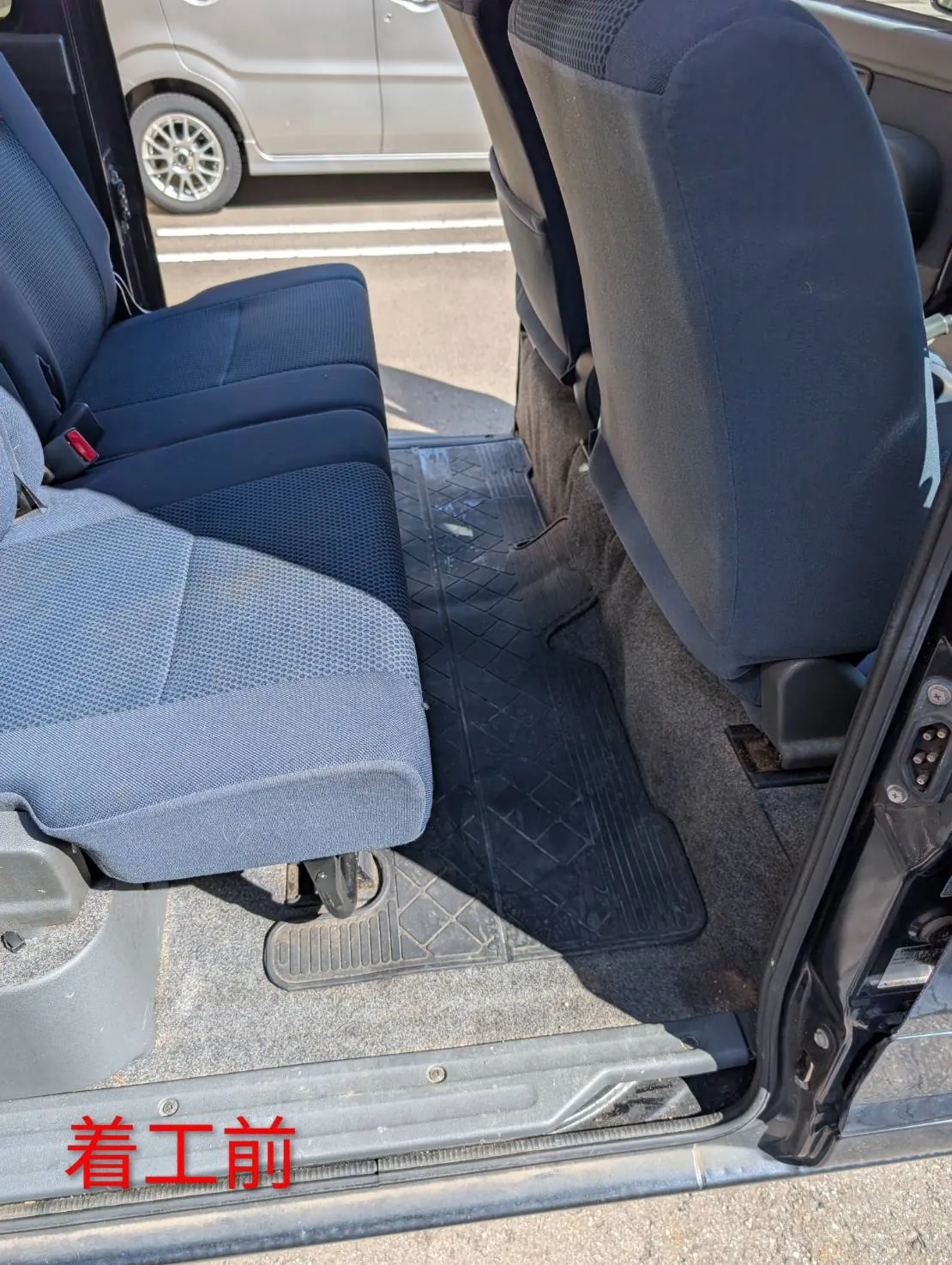 着工前の後部座席の足元。黒いゴム製のマットと、まわりのグレーのカーペット