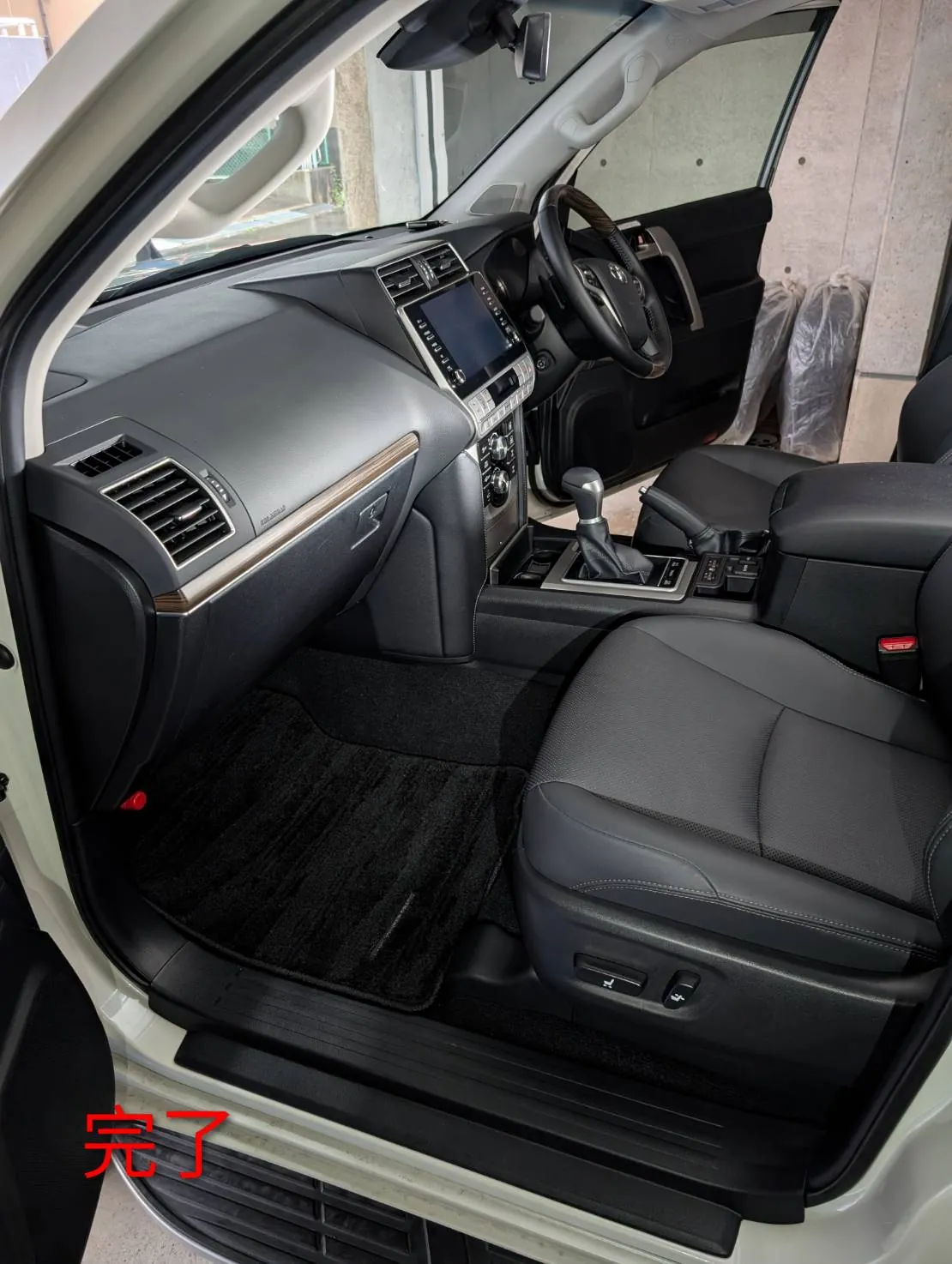 完了した運転席まわり。ハンドル、ナビ画面、シフトレバーが写り、手前の足元に黒いフロアマットが敷かれている