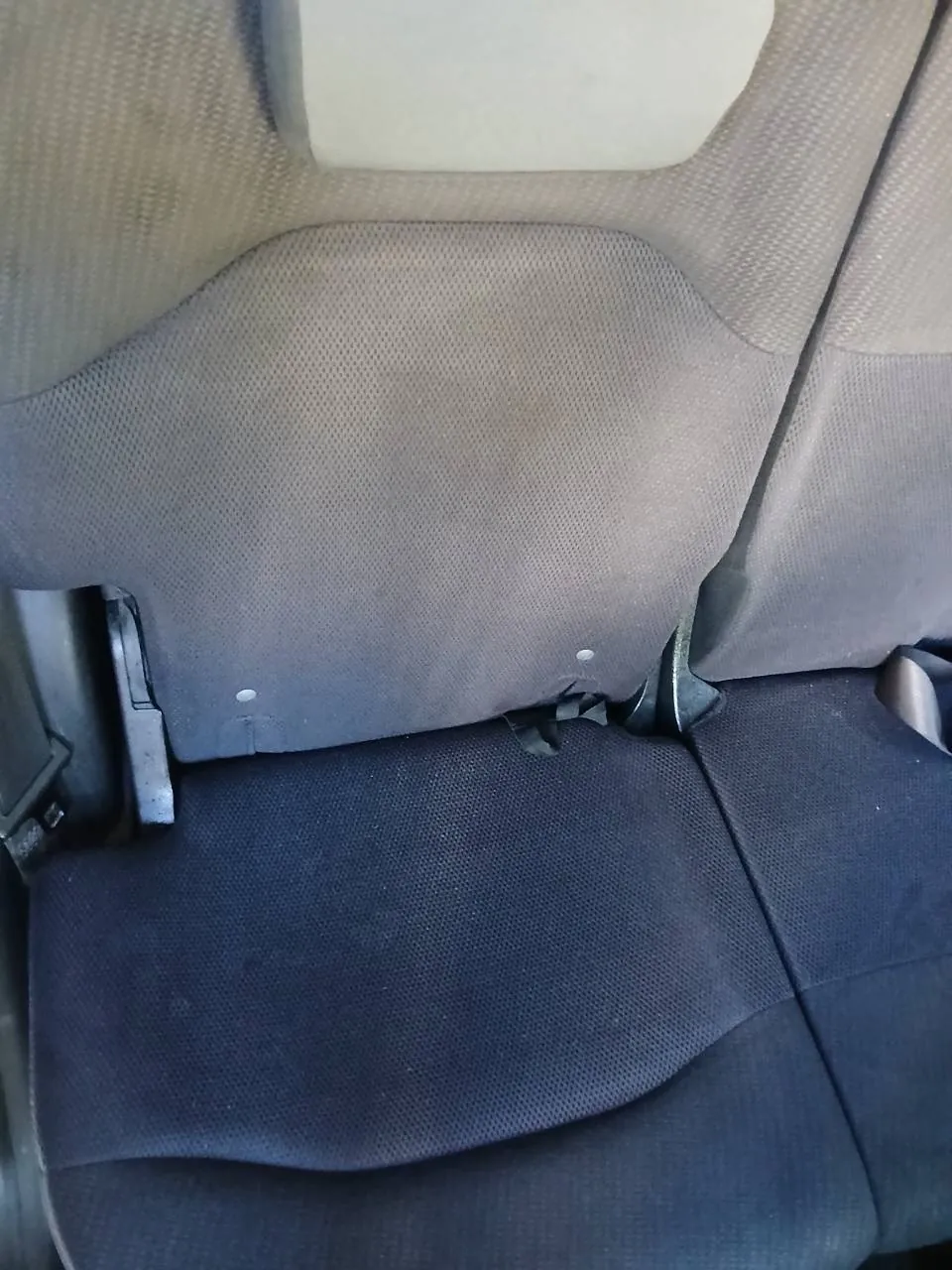 後ろの席を片側のドアから見たところ。背もたれを前に倒せるタイプで、左に黒い金具が付いている